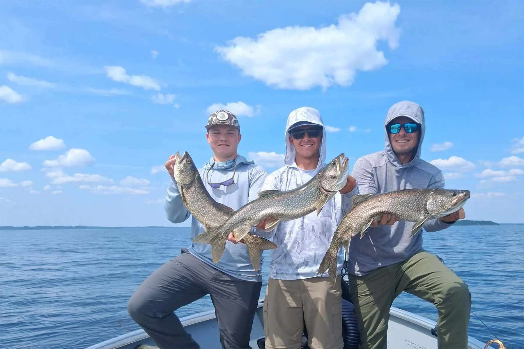 Three Cat Island Lodge guests holding lake trout on Trout Lake