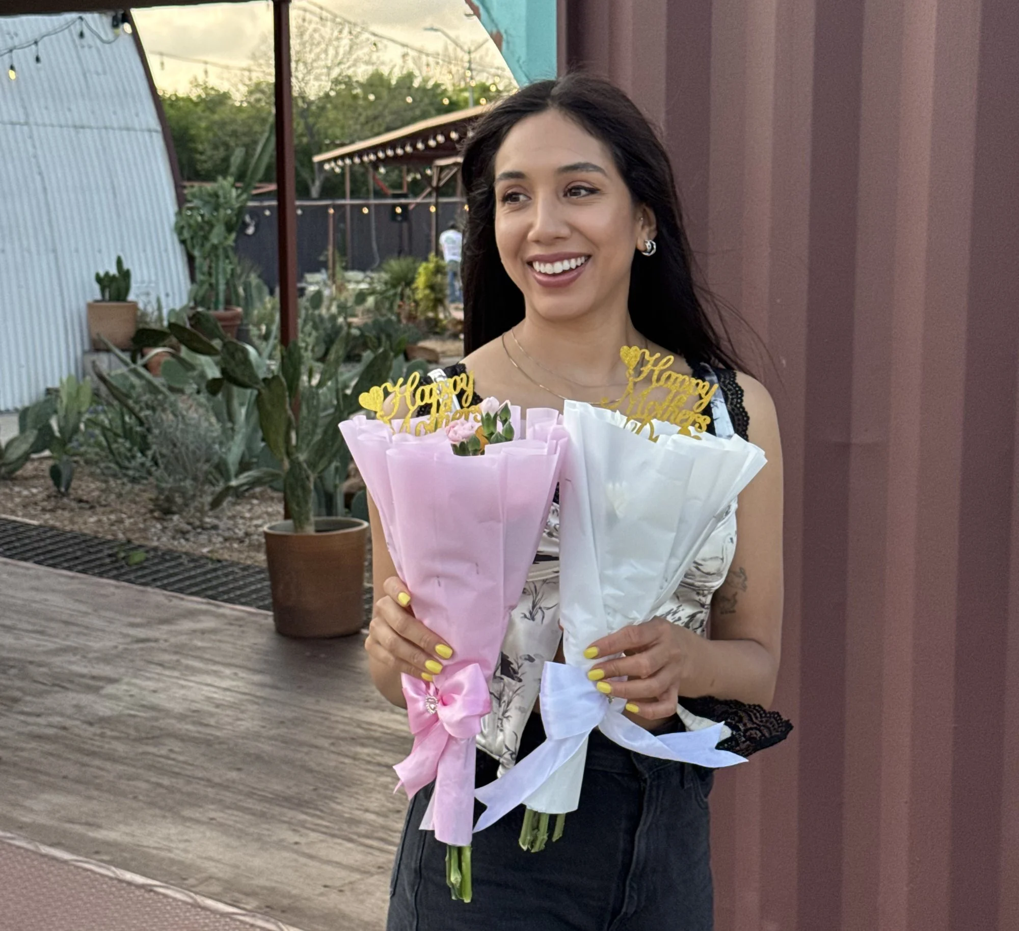 Vanesa Acosta, RN and Licensed Esthetician, holding two Happy Mother's Day bouquets at Face It Dermalab Dallas
