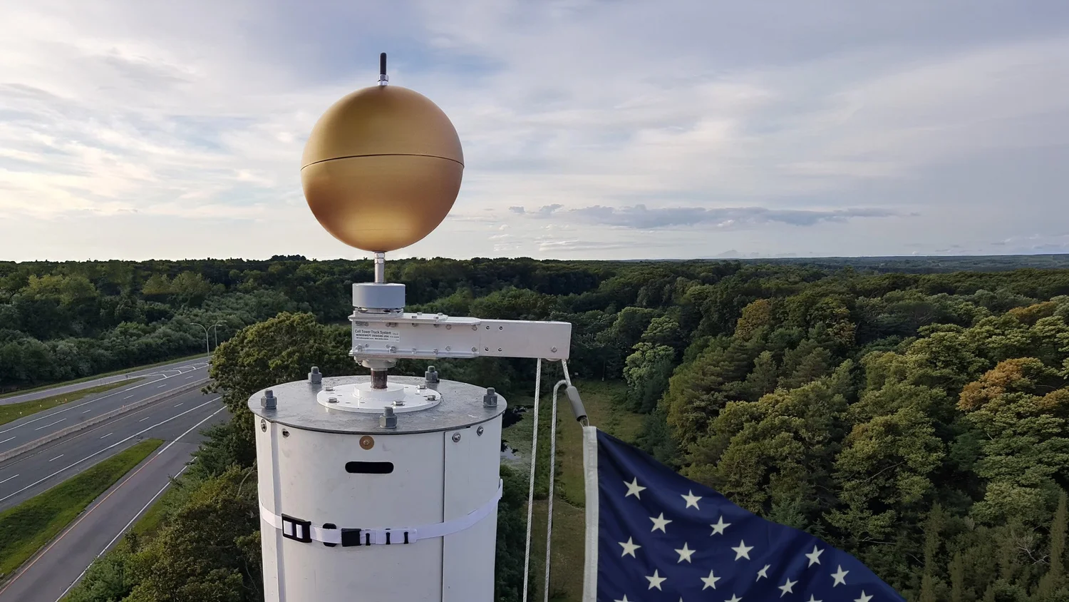 SwingArm Truck and gold Finial Ball on a concealment tower, with a WindBand on the shroud below