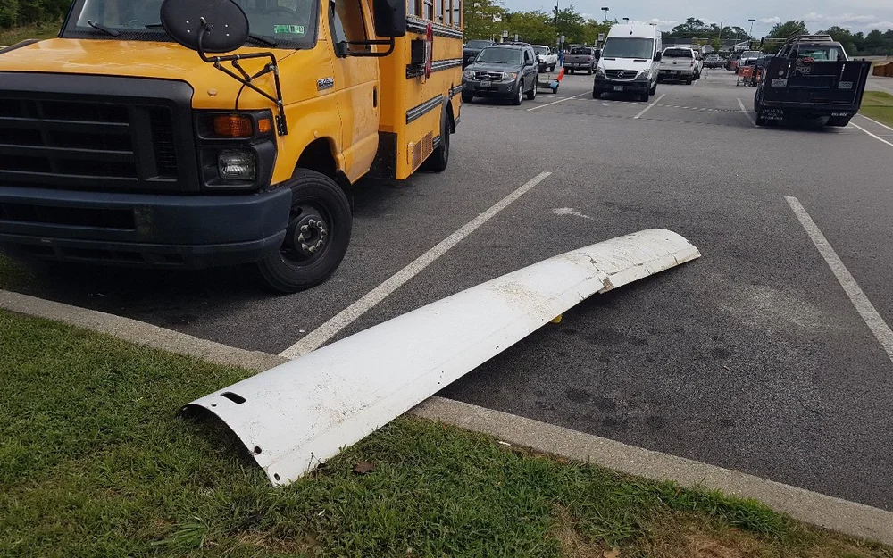 A concealment shroud that fell from a cell tower lying in a parking lot beside a school bus