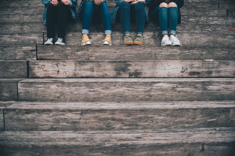 Group of young people sitting together on wooden steps