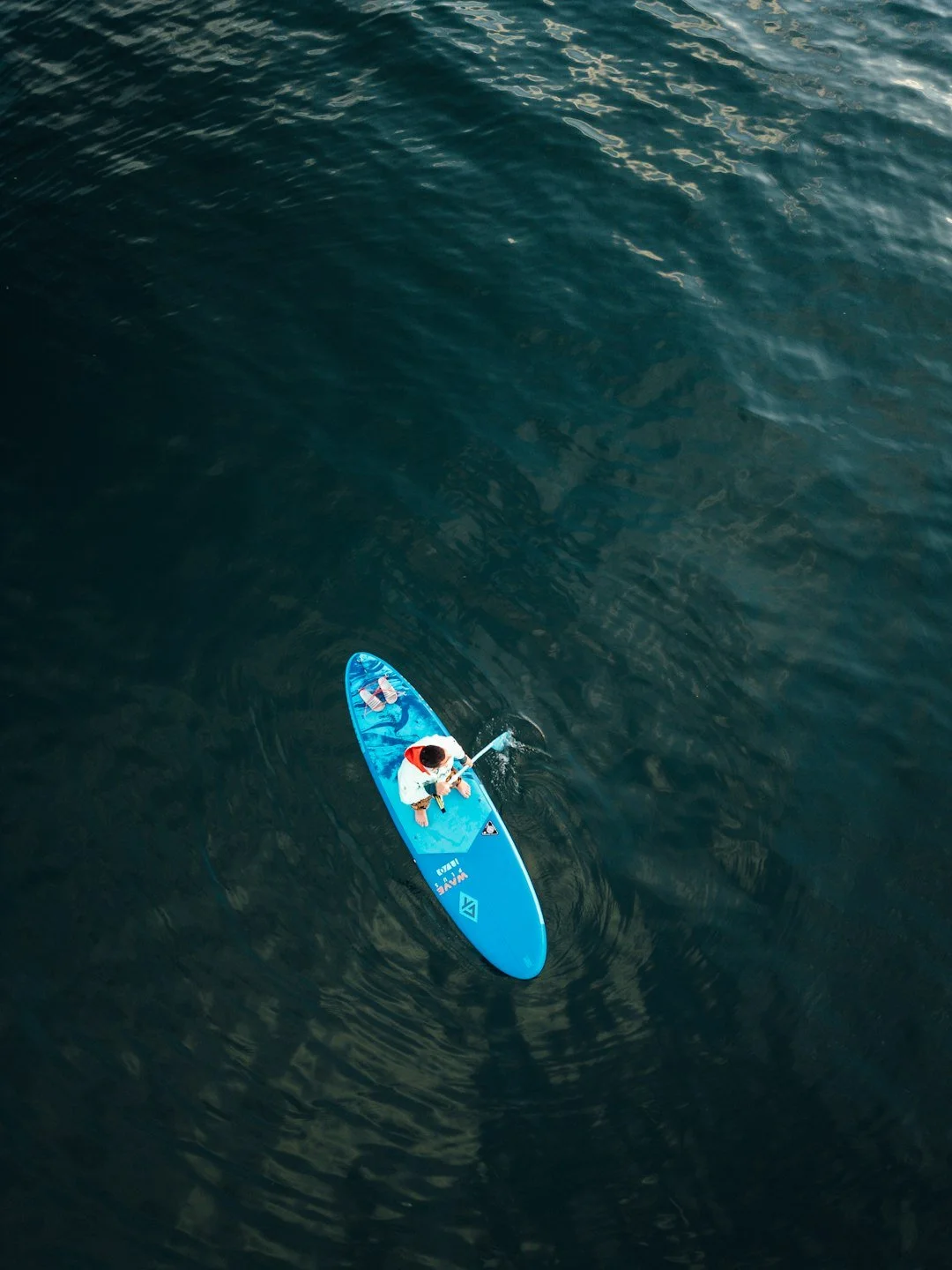 Person paddleboarding on calm ocean water