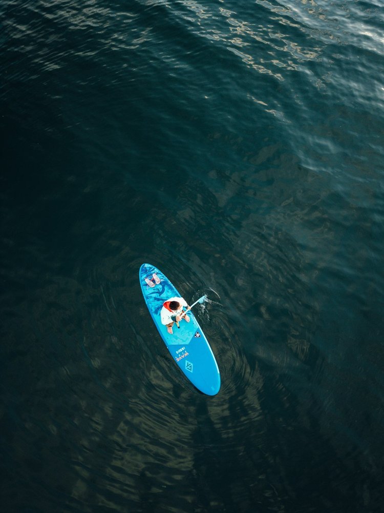 Person paddleboarding on calm ocean water