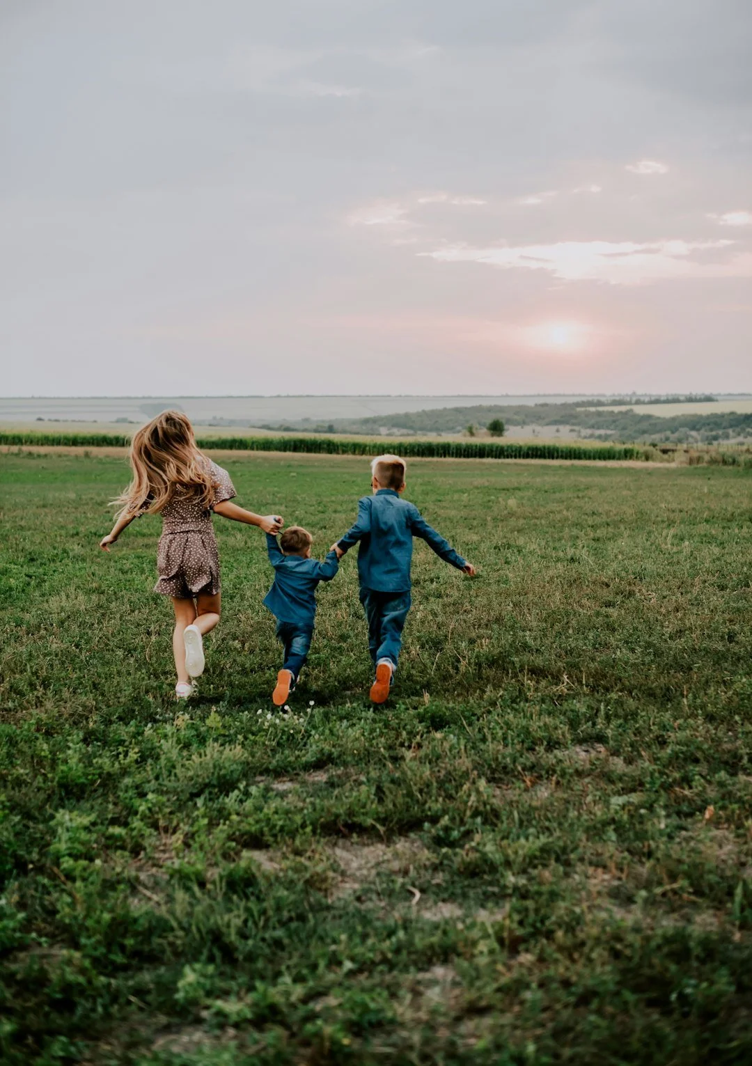 Children running together through a grassy field