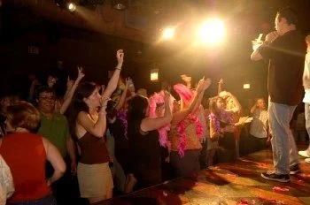 Audience members with arms in the air at Excalibur in Chicago, a performer on stage