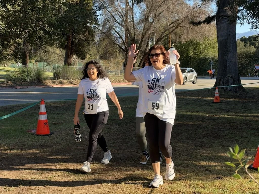 Two runners wave as they head toward the finish