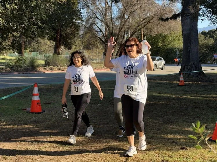 Two runners wave as they head toward the finish