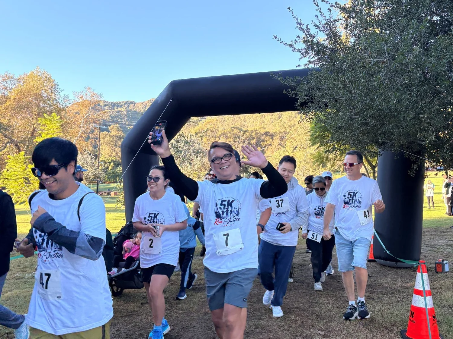 Runners wave and celebrate as they come through the 5K arch