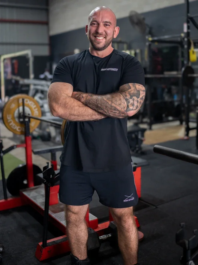 Lewis McKenzie standing in the gym with his arms crossed