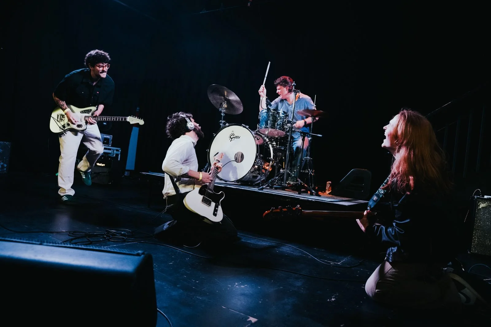 Willingdon performing live - guitars, drums, and bass on a dark stage