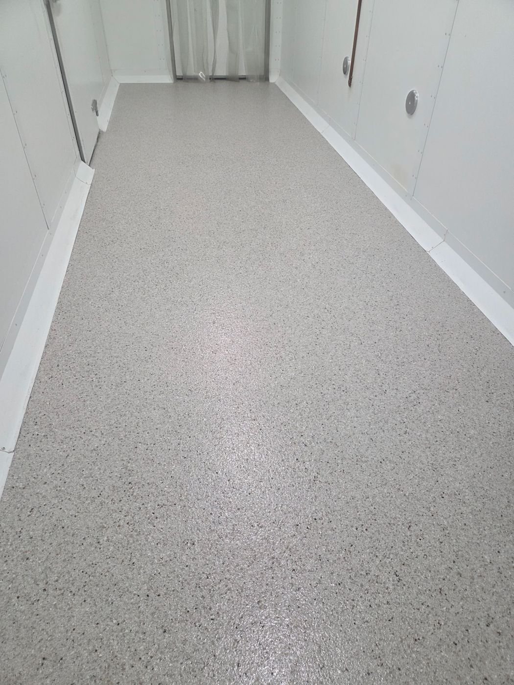 Speckled quartz floor with cove base in a cold-storage corridor