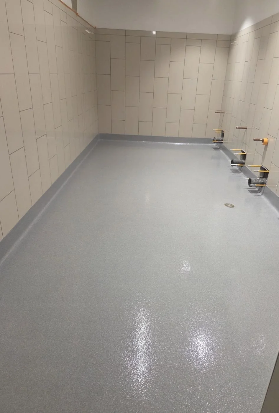 Gray quartz floor with integral cove base in a commercial shower room