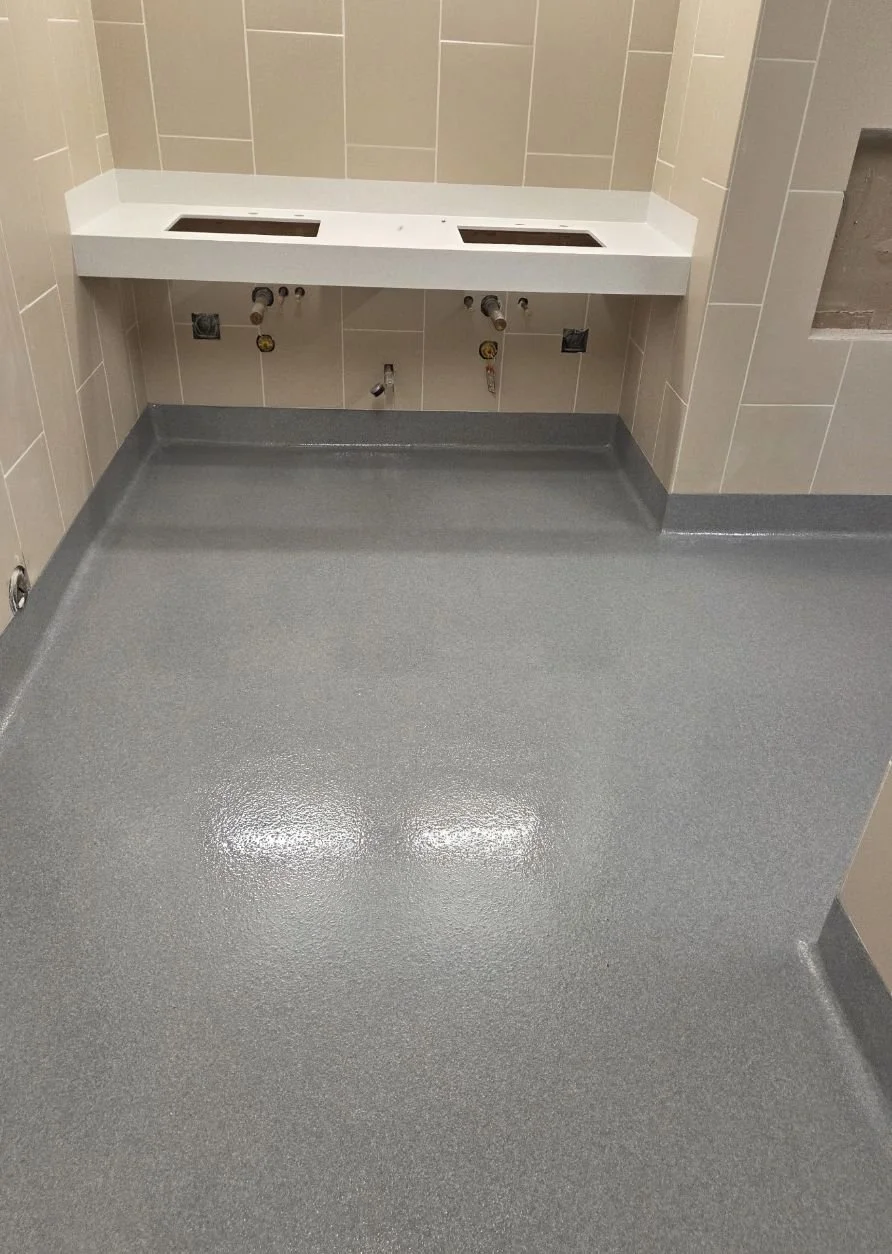 Gray quartz restroom floor with integral cove base under a vanity