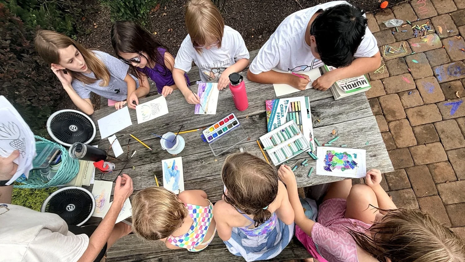 Kids painting together at a Clubhouse craft club with a staff member