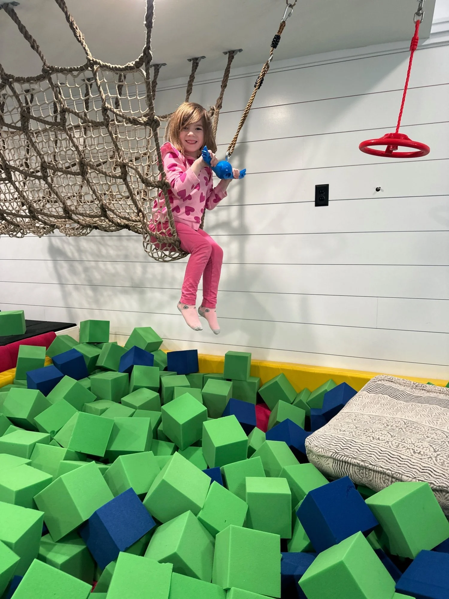 Girl on rope swing over foam pit at indoor play space near King of Prussia