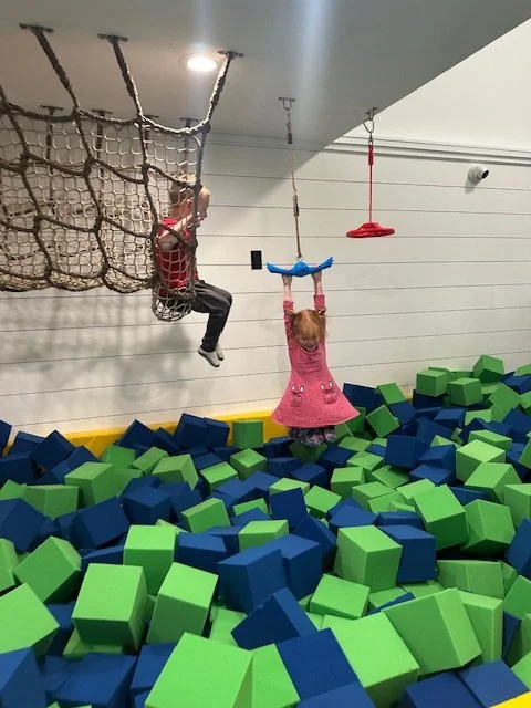 Kids climbing cargo net over foam pit at indoor playground summer camp Phoenixville PA