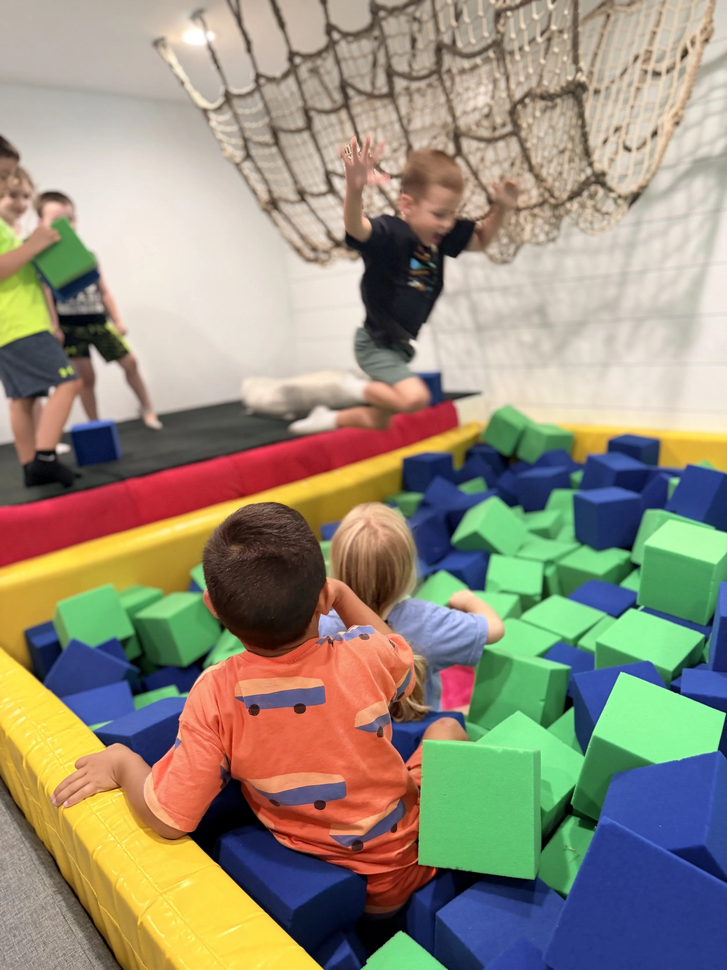 A child jumping into the foam pit from the climbing net