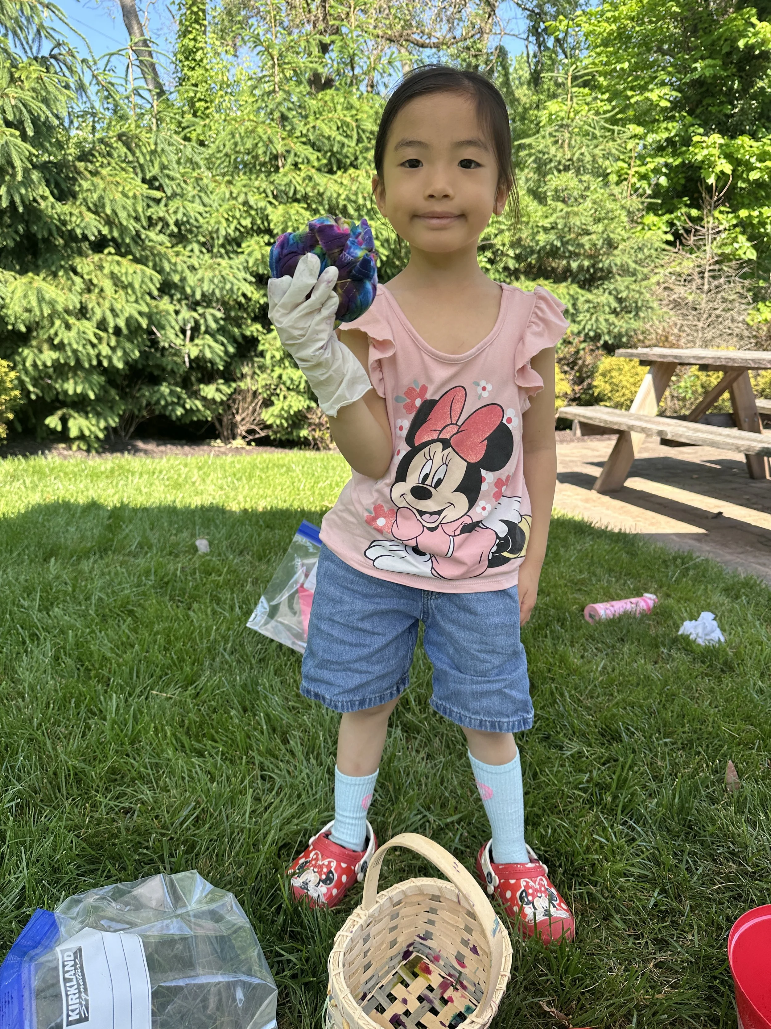 Young girl showing off her finished tie-dye shirt at camp