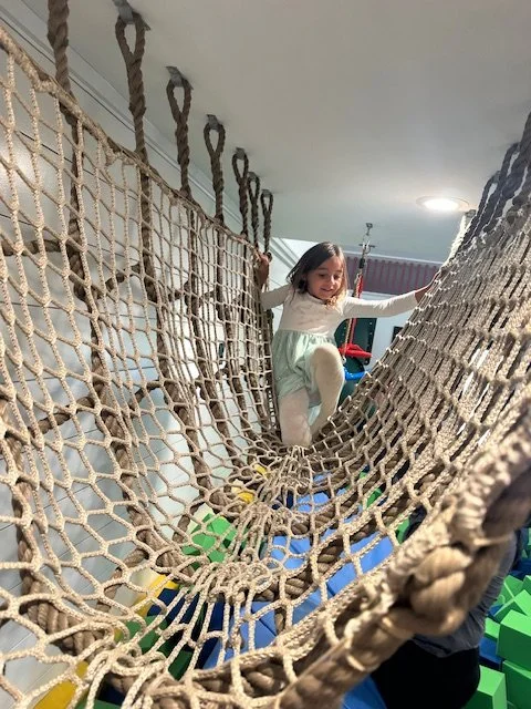 Child climbing an indoor rope net bridge at The Clubhouse — things to do with kids in Phoenixville PA