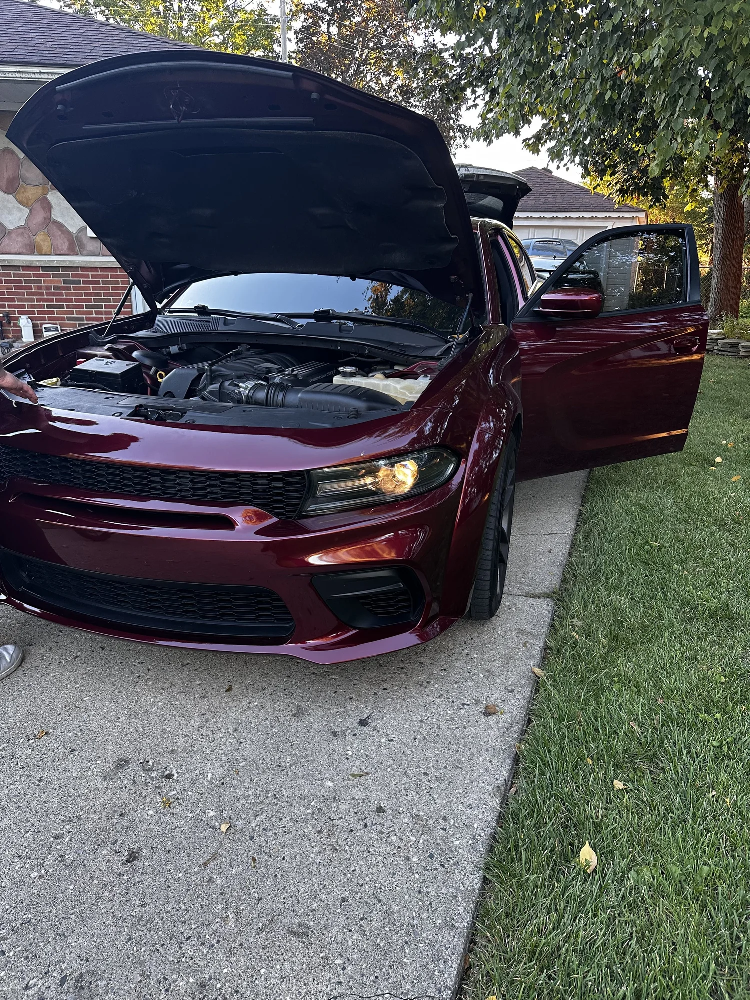 Burgundy Dodge Charger with its hood and driver door open during a Corsa Nero installation
