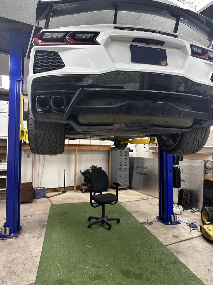 White C8 Corvette on a lift for a Corsa Nero GPS and kill switch installation