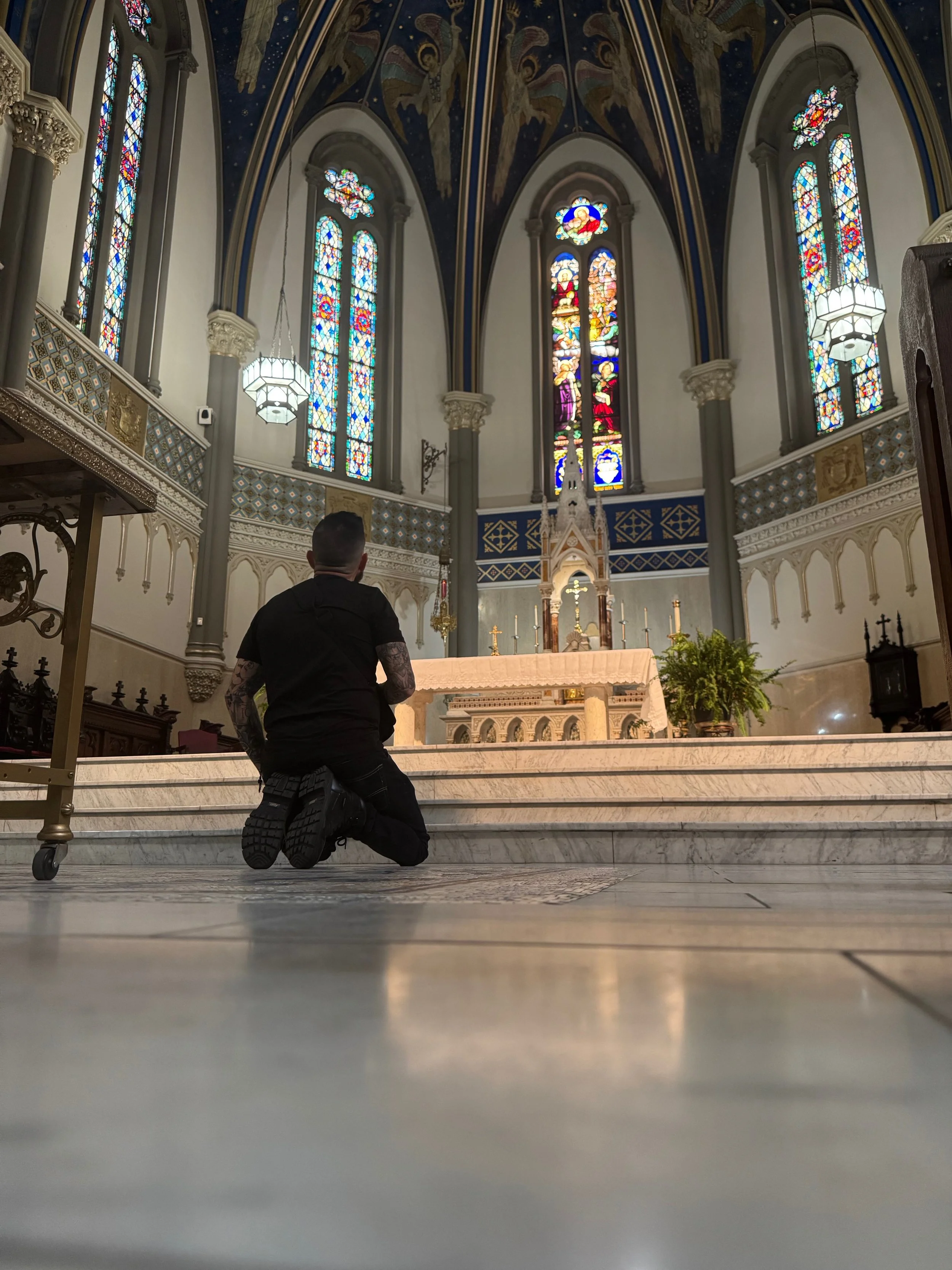 A man kneeling in prayer before the altar inside a Catholic church
