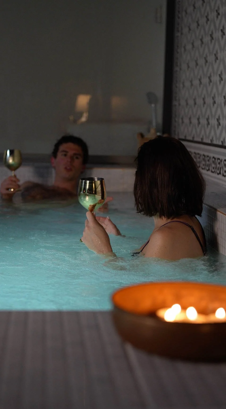 A couple with glasses of cava in the candlelit jacuzzi