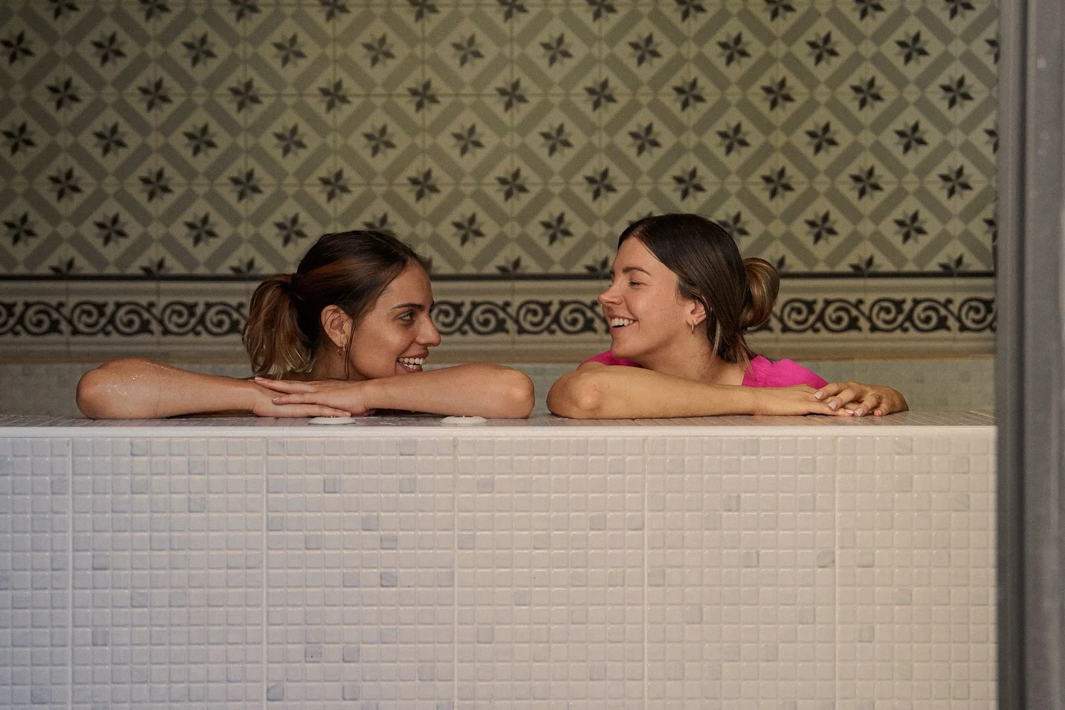 Two guests relaxing in the private jacuzzi beneath the patterned tiles