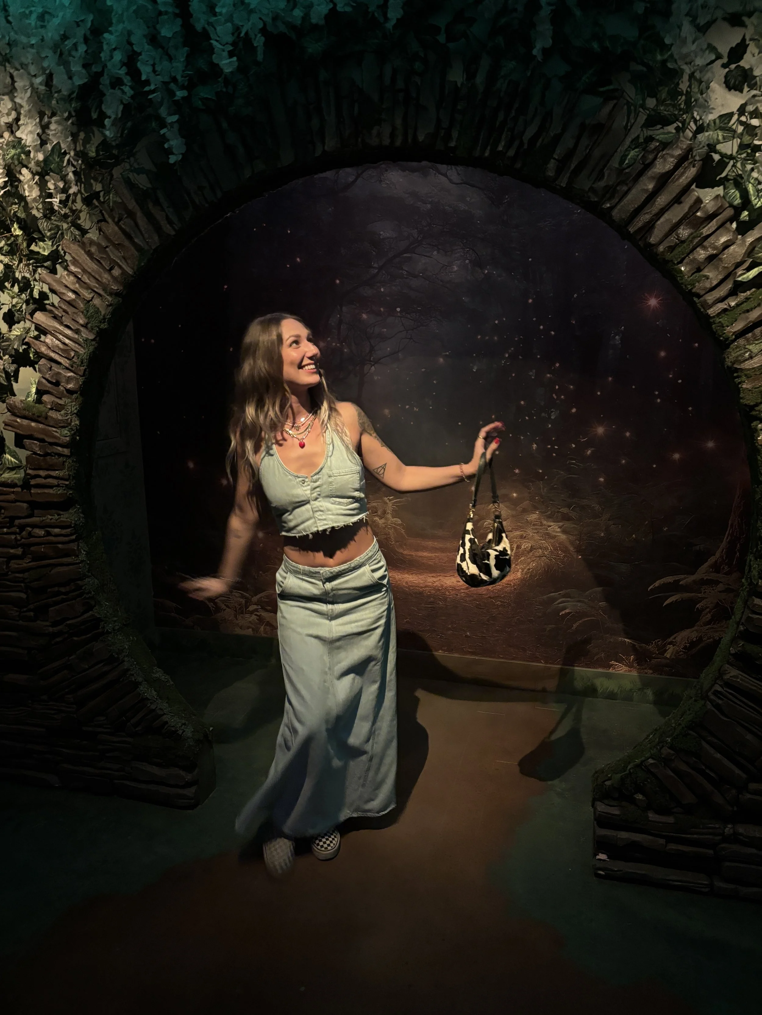 Sadie smiling beneath a stone archway with a starry woodland backdrop
