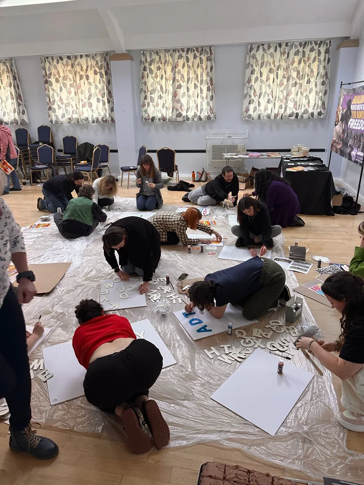 Bootcamp attendees painting protest signs on the floor