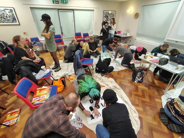 Activists kneeling on the floor stencilling protest banners together