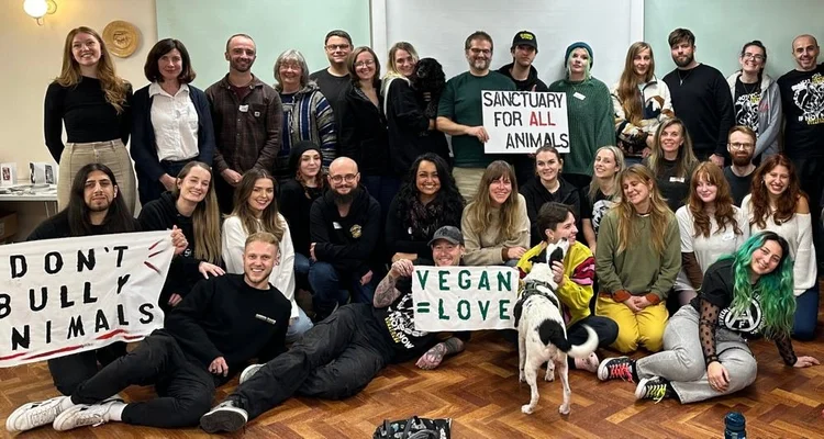 Large smiling group of bootcamp attendees with Sanctuary for all animals and Vegan equals love signs, and a dog