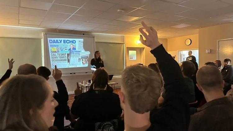 Audience raising hands during a talk about a local campaign that made the newspaper