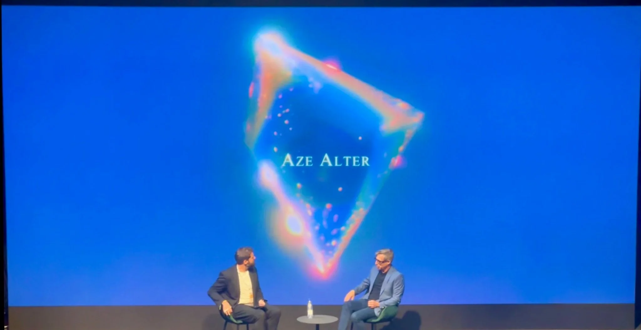 Onstage discussion with Aze Alter's name projected behind the speakers