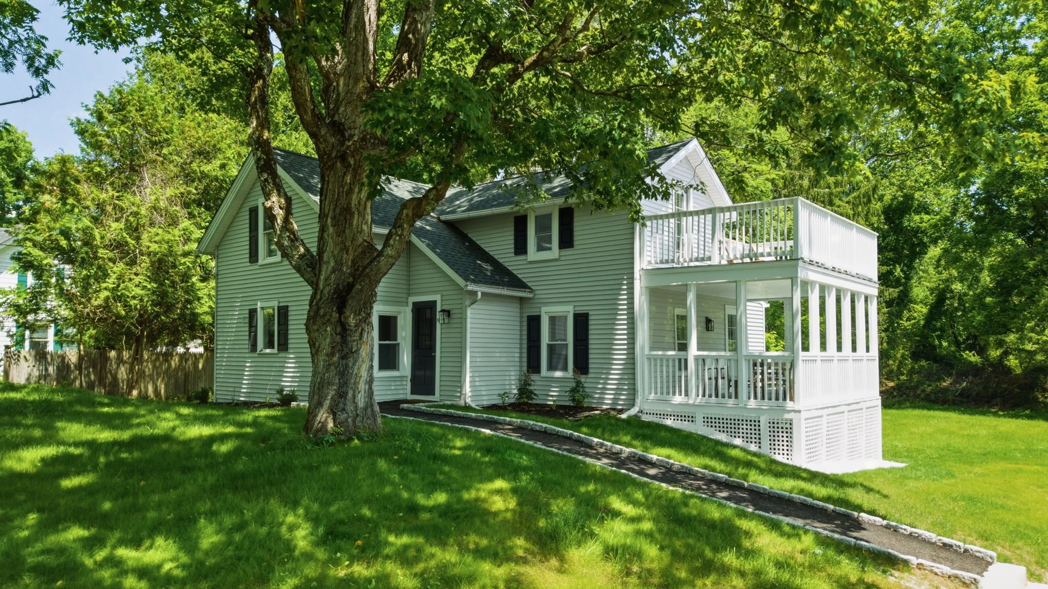 Mystic Cash 4 Homes project in Lakeville, Connecticut, with a white two-story porch and tree-lined yard
