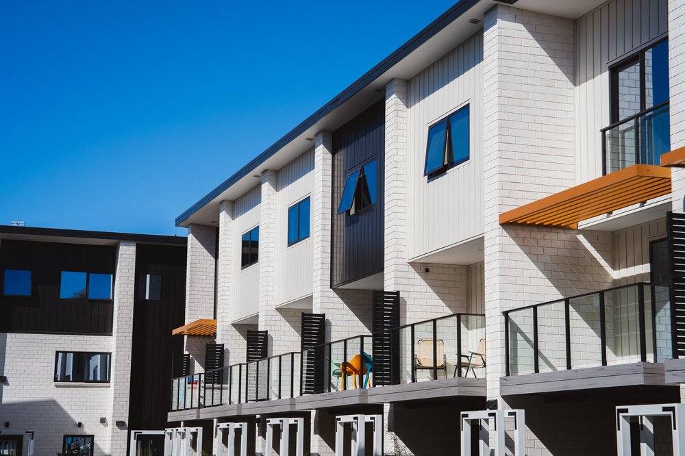 White brick townhouses with glass balconies and ochre sunshades at 200 Carrington Road, Mount Albert