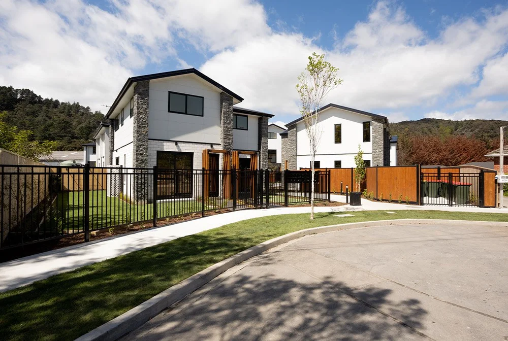 White townhouses with stone accents, fenced gardens and planting at 4 Johnston Grove, Lower Hutt