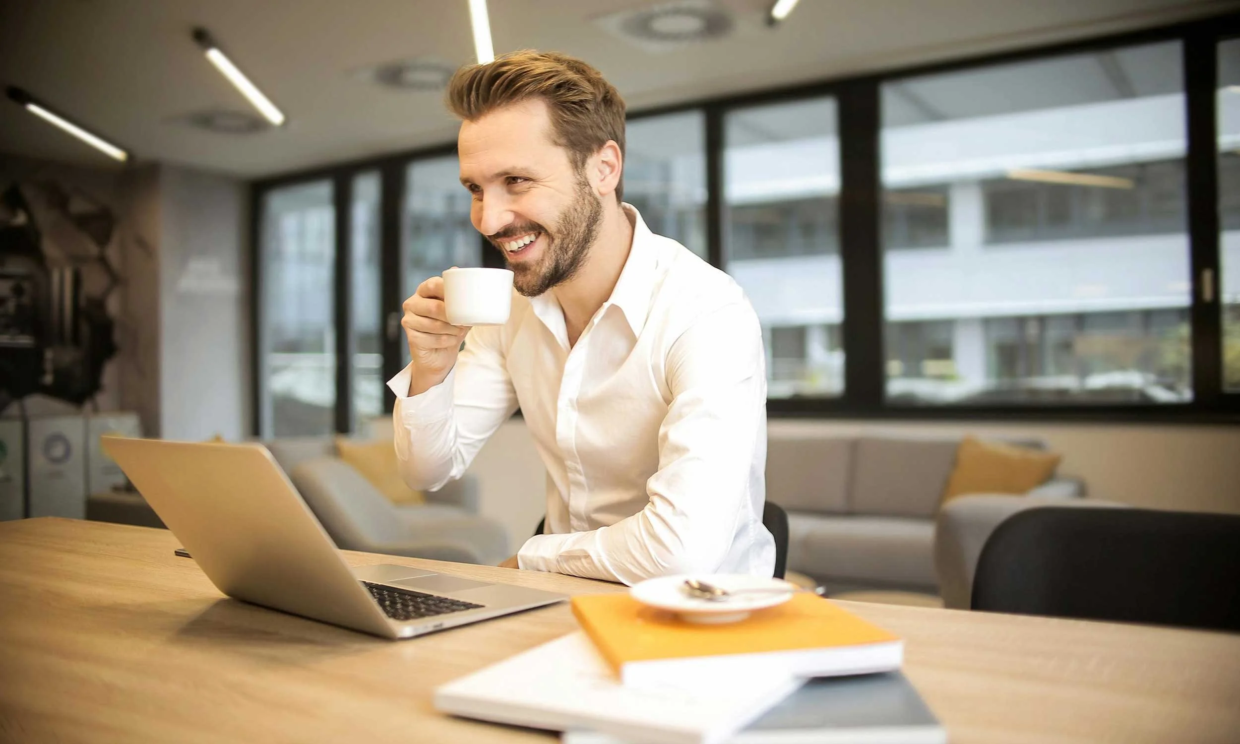 Small business owner smiling and welcoming new customers into a cozy shop, café, or office. Warm lighting, friendly atmosphere, focus on human connection.