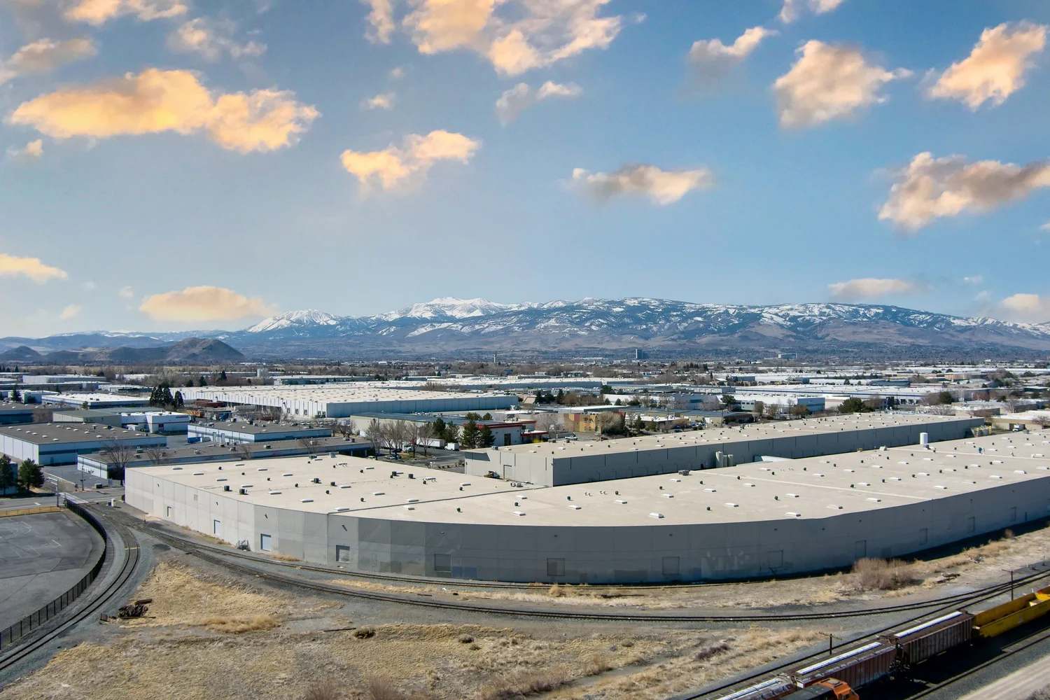 Aerial view of an industrial warehouse and rail spur in the Reno-Sparks industrial submarket, with the Sierra Nevada foothills in the background