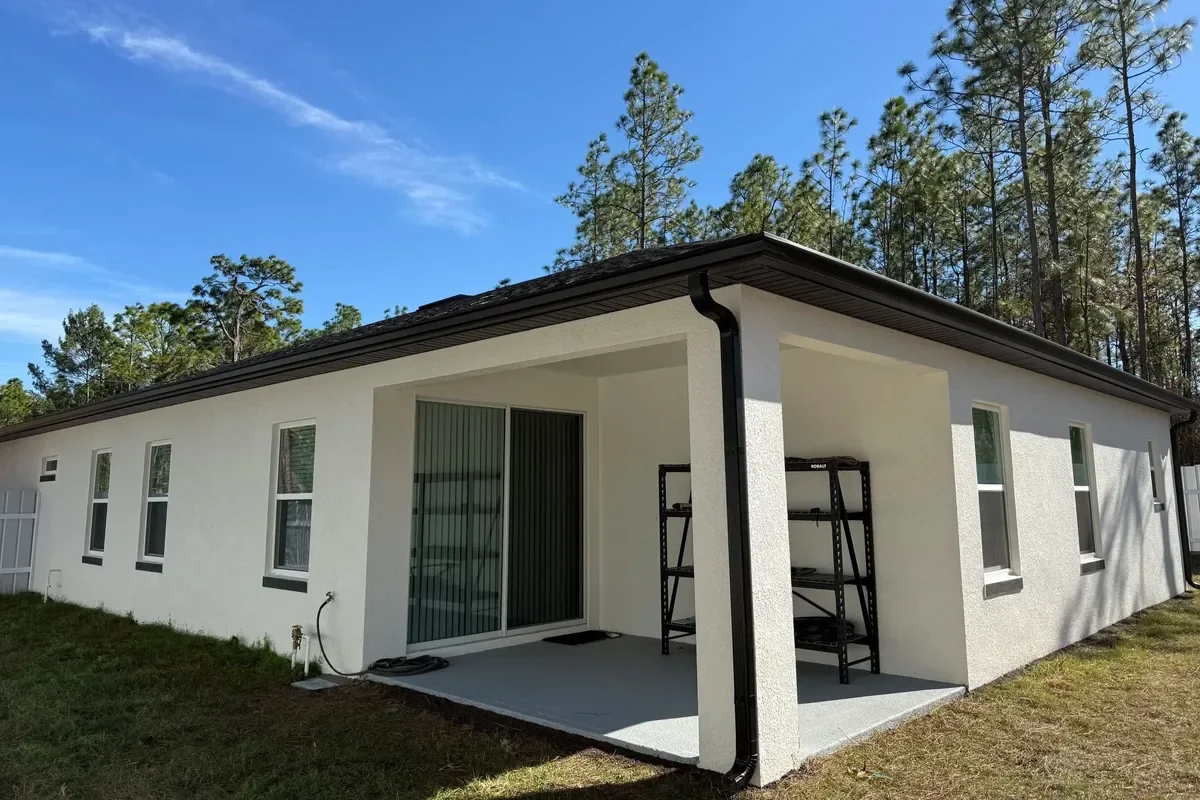 Black seamless gutters installed around the roofline and covered patio of a home in Marion Oaks, Florida.