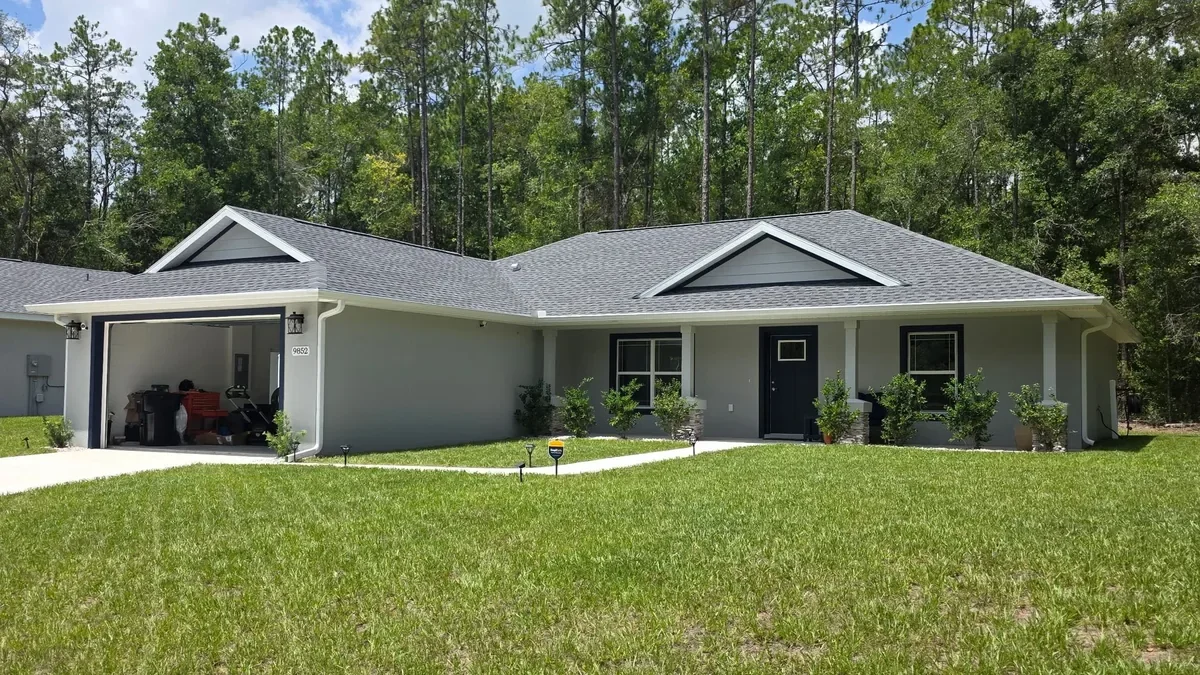 White seamless gutters installed on a gray home with a covered entry in Citrus Springs, Florida.