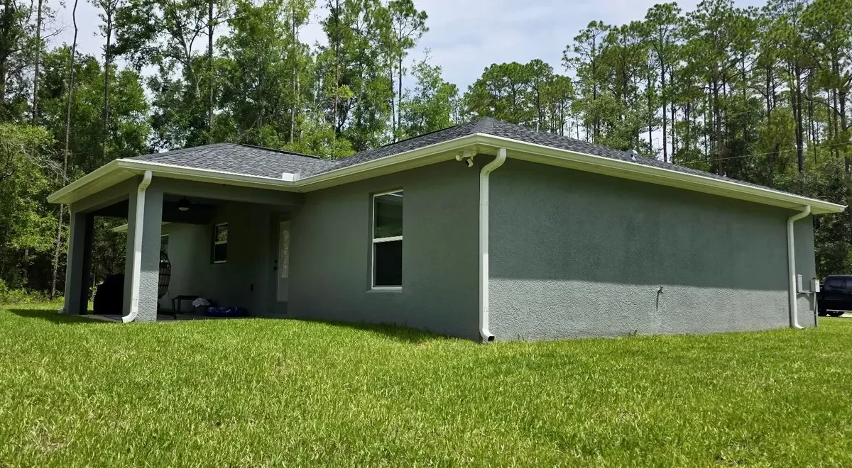 White seamless gutters and downspouts installed on a gray home in Citrus Springs, Florida.