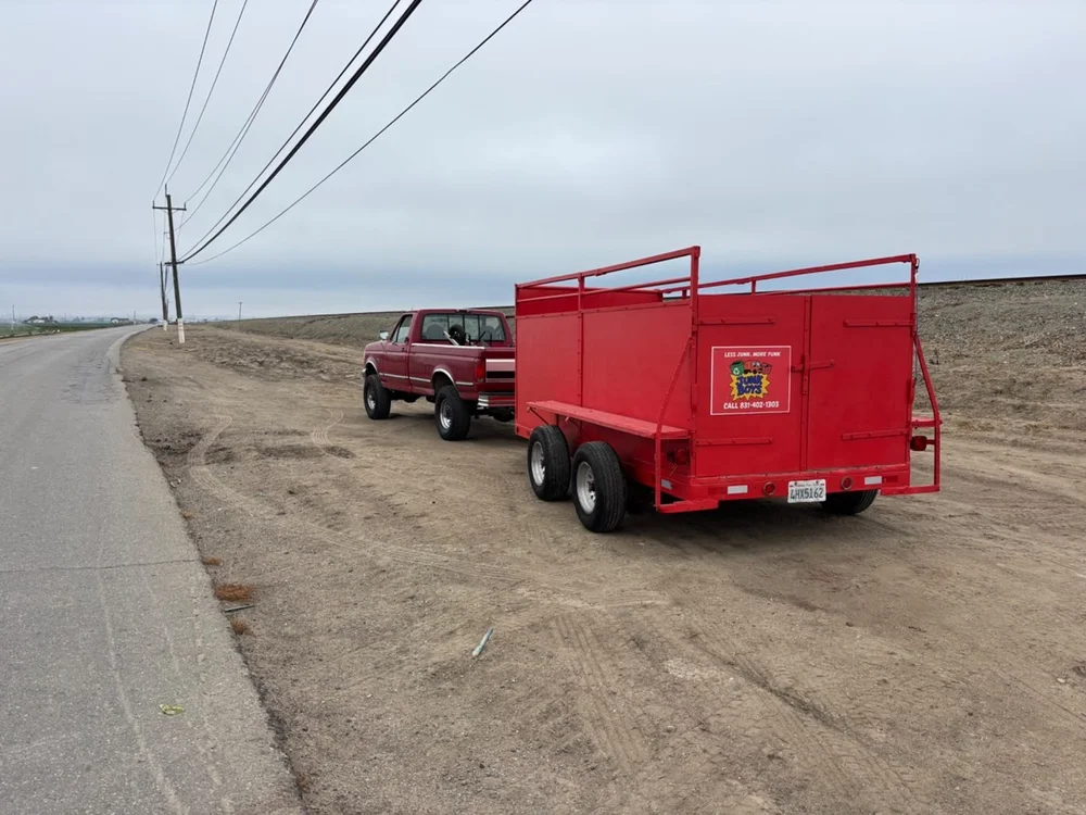 Junk Boys red hauling trailer and pickup parked beside a road