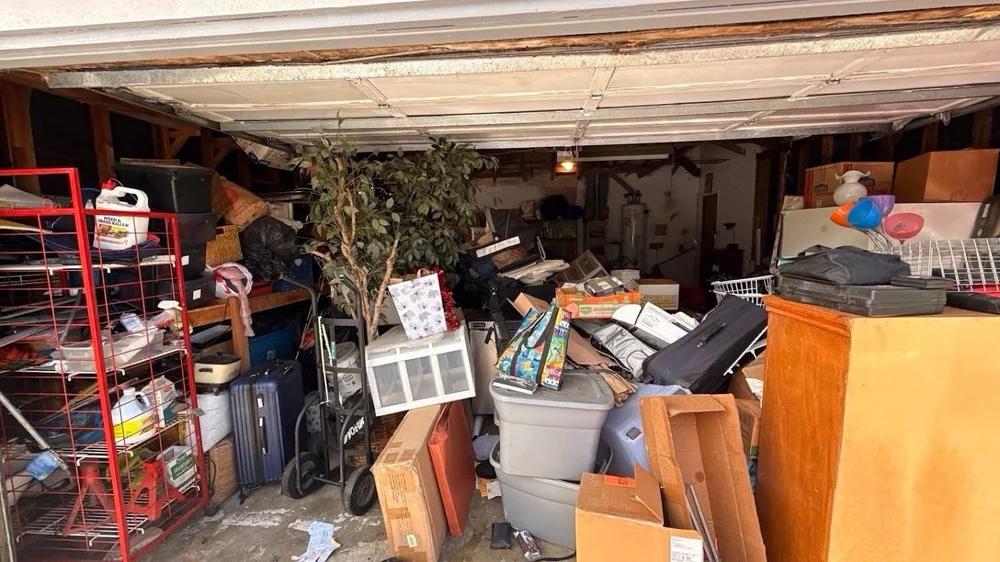 Garage filled with furniture, boxes, and stored clutter before Junk Boys cleanout