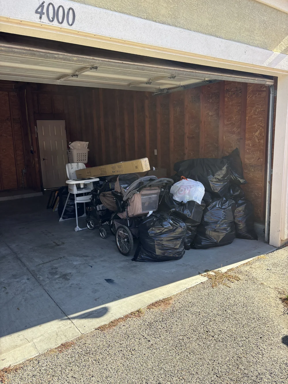 Garage before pickup with bagged clutter, a stroller and household items