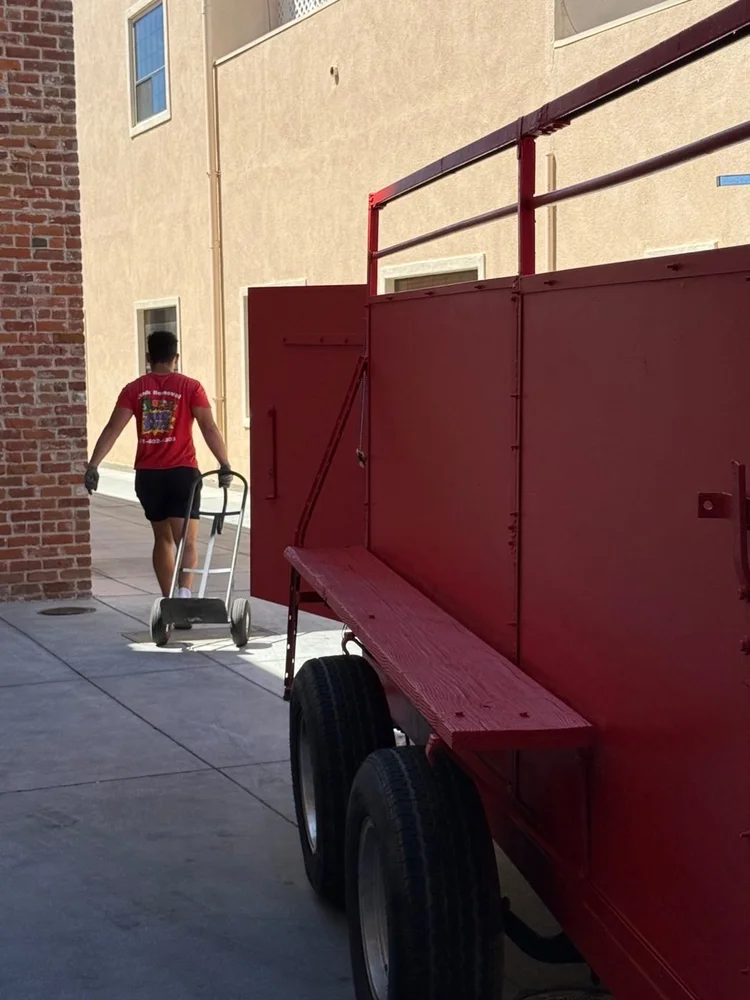 Junk Boys crew member using a hand truck beside the trailer