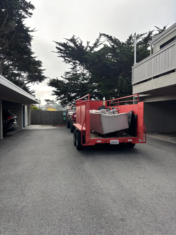 Junk Boys trailer carrying furniture beside residential garages