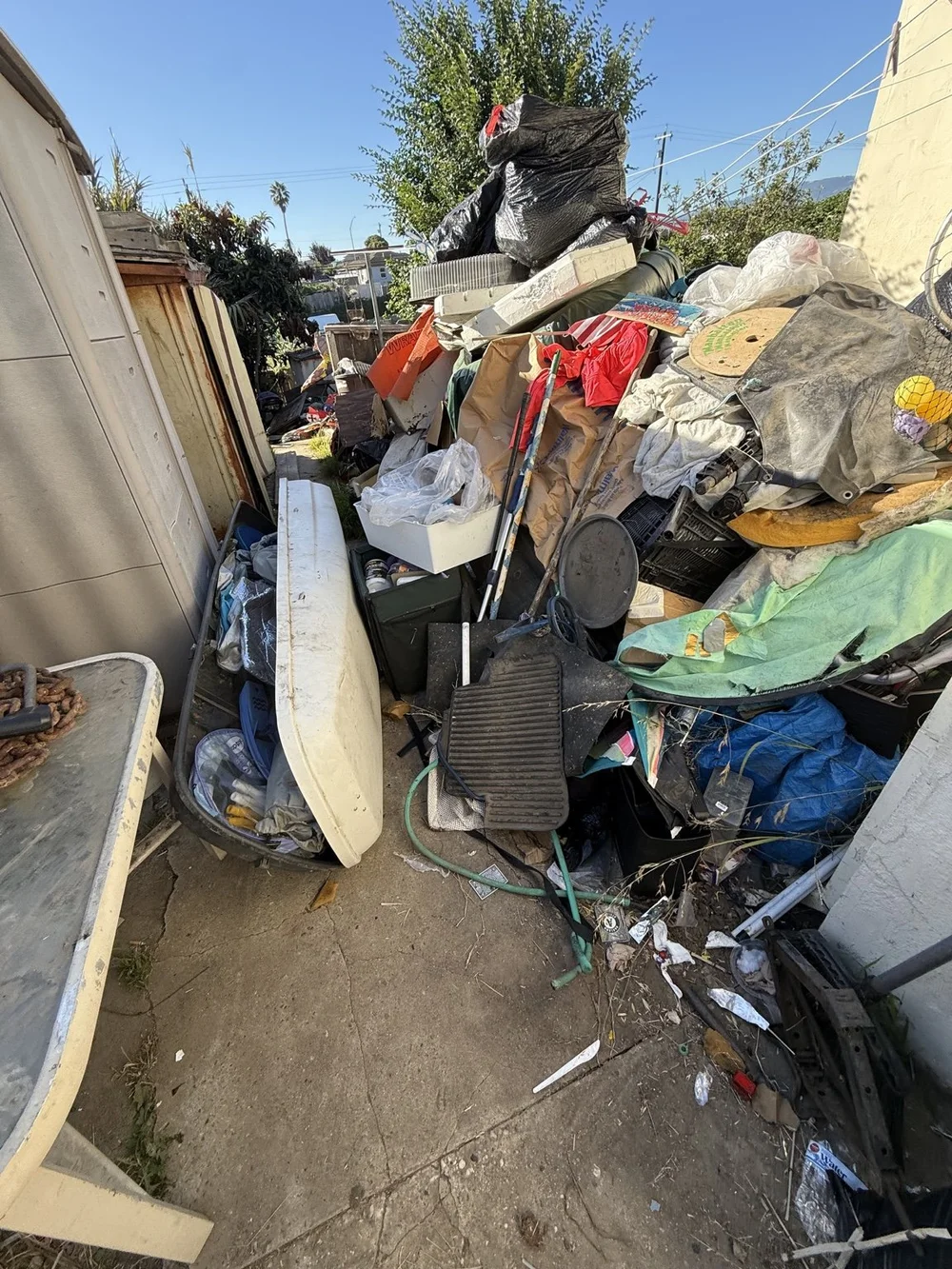 Large accumulation of household items beside the house before a hoarding cleanout