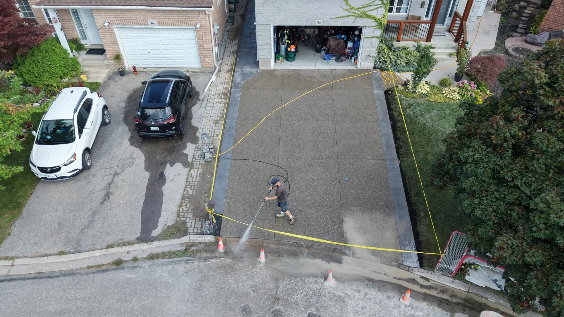 Exposed aggregate concrete driveway with charcoal border being pressure washed in St. Catharines