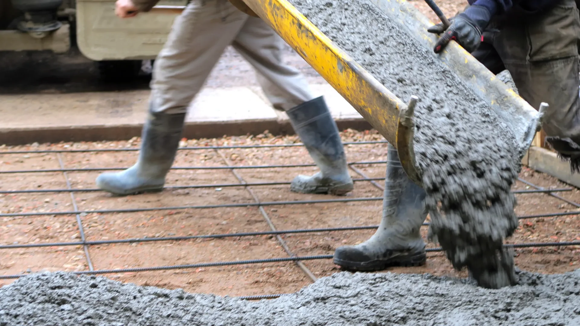 concrete pouring from chute onto rebar for a driveway slab